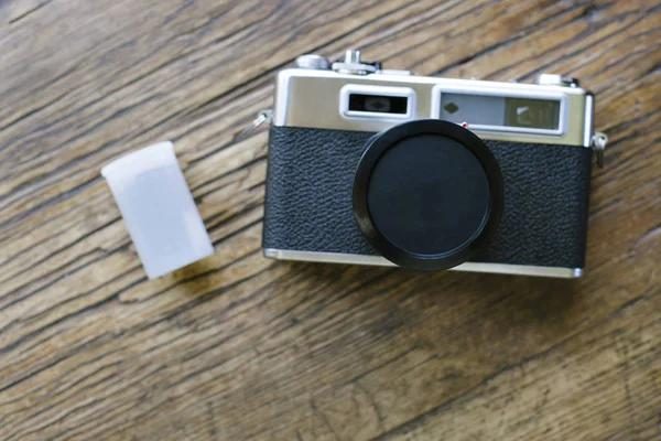 Retro rangefinder camera and film rolls on a wooden table