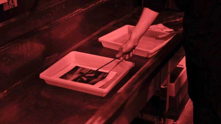 Handling a print with tongs under red safelight